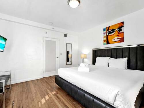 Large bed in room with colorful painting on wall